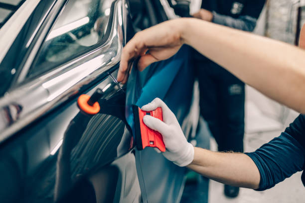 Car wrapping specialist putting vinyl foil or film on car. Selective focus